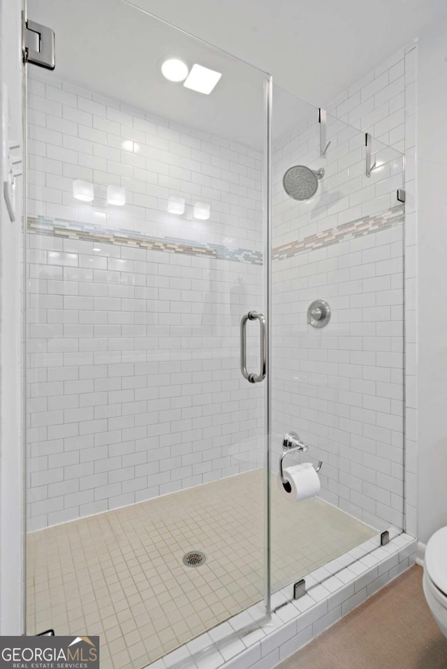 full bathroom featuring a shower stall and toilet