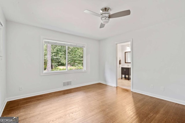 interior space with a ceiling fan, visible vents, baseboards, and wood finished floors