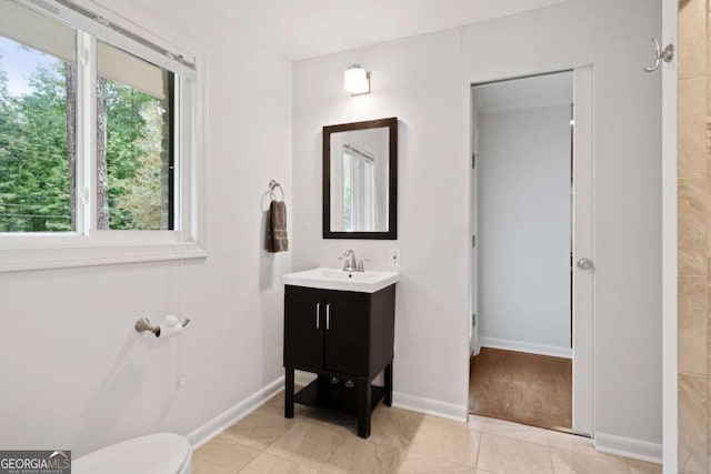 bathroom featuring toilet, vanity, and baseboards