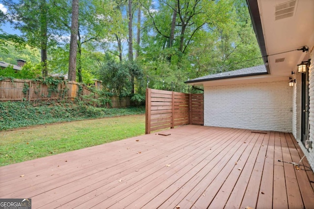 wooden terrace featuring a fenced backyard and a yard