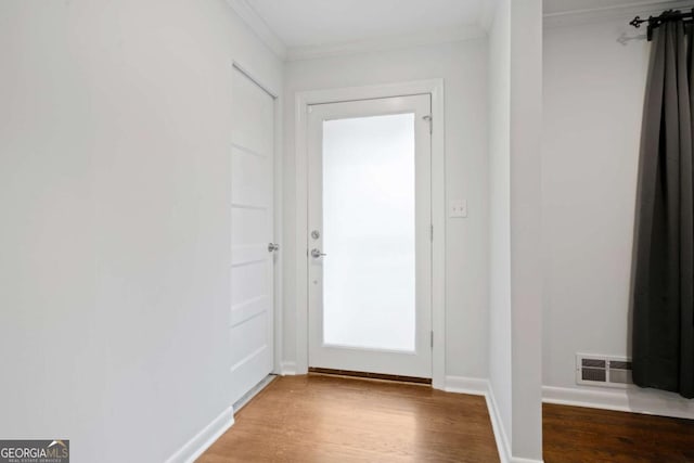 doorway with visible vents, crown molding, and wood finished floors