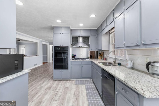 kitchen featuring gray cabinetry, a warming drawer, wall chimney range hood, and black appliances