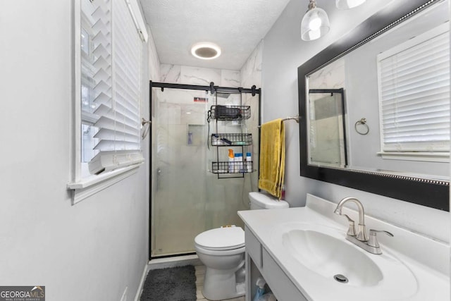 full bath with a textured ceiling, vanity, a shower stall, and toilet