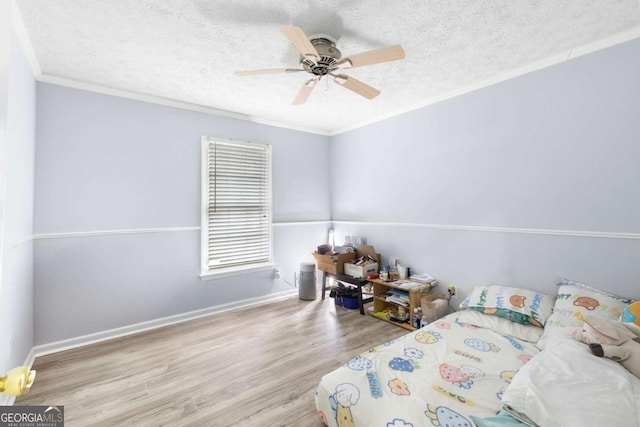 bedroom featuring baseboards, ceiling fan, ornamental molding, wood finished floors, and a textured ceiling