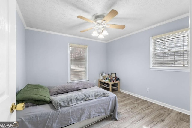 bedroom featuring crown molding, a textured ceiling, baseboards, and wood finished floors