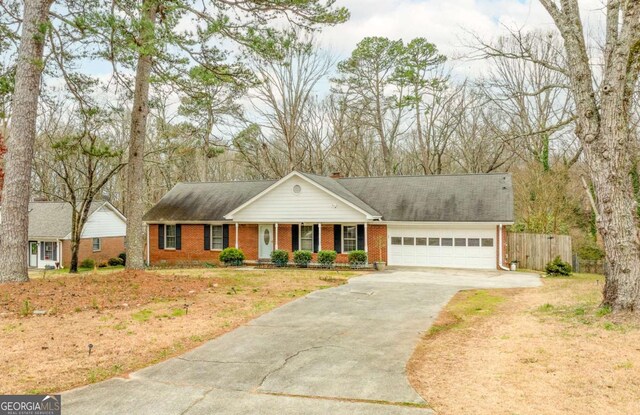 view of front facade with brick siding, a chimney, concrete driveway, an attached garage, and fence