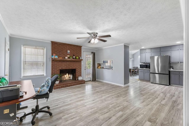 office with ornamental molding, light wood finished floors, a fireplace, and a wealth of natural light