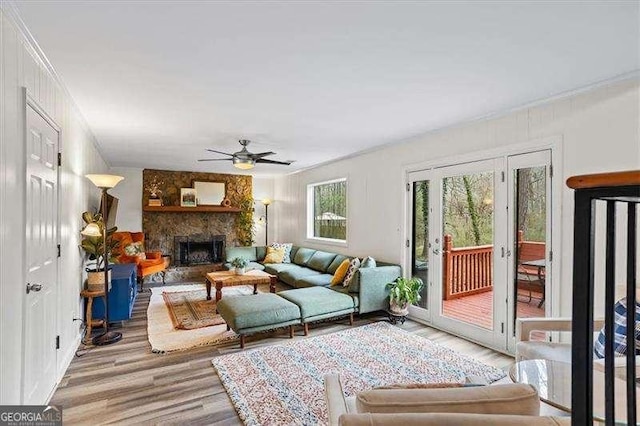 living area with ceiling fan, crown molding, a fireplace, and wood finished floors