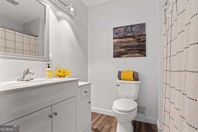 full bathroom with visible vents, toilet, vanity, wood finished floors, and baseboards