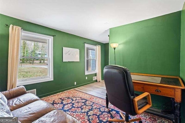 home office featuring visible vents, baseboards, and wood finished floors