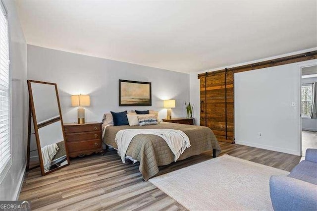 bedroom featuring a barn door and light wood-type flooring