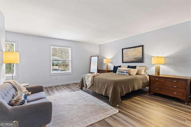 bedroom featuring light wood finished floors and baseboards