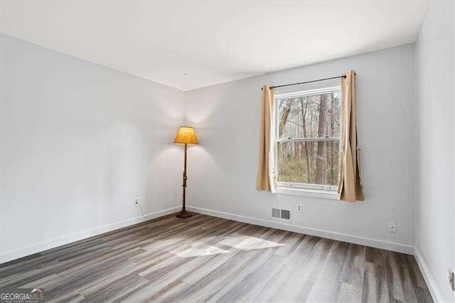 empty room with visible vents, baseboards, and wood finished floors