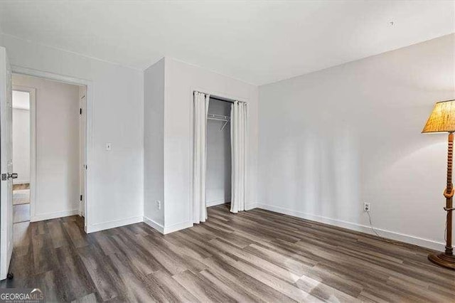 unfurnished bedroom featuring a closet, wood finished floors, and baseboards