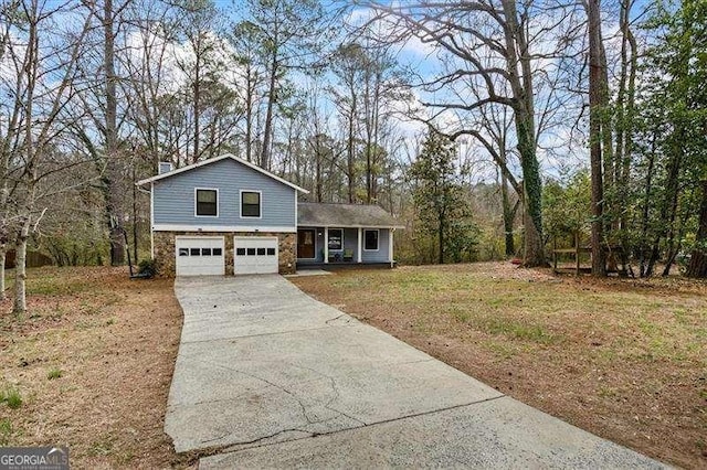 tri-level home with a garage, stone siding, concrete driveway, and a front yard