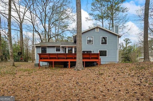 rear view of property featuring a chimney and a deck