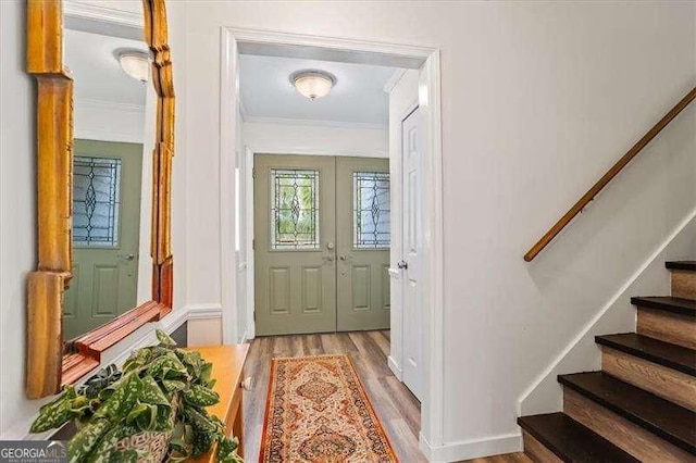 foyer with stairs, wood finished floors, and crown molding