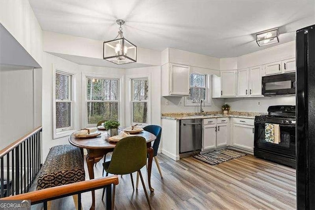 kitchen with black appliances, a wealth of natural light, a sink, and wood finished floors