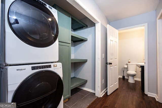 washroom with stacked washer and dryer, laundry area, baseboards, and dark wood-style floors