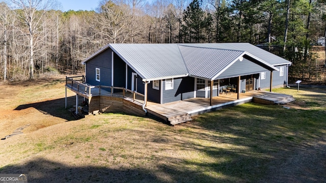 back of property with metal roof, a yard, a forest view, and a wooden deck