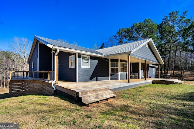 back of property featuring metal roof, a lawn, and a wooden deck