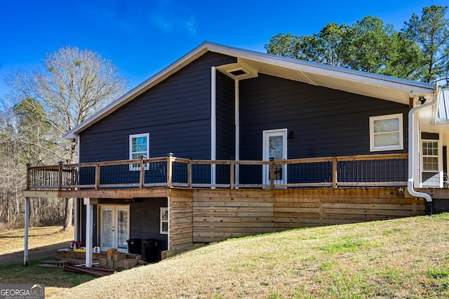 rear view of house featuring a deck, french doors, and a lawn