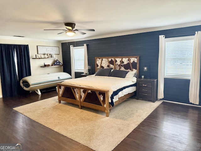 bedroom featuring ceiling fan, ornamental molding, wood finished floors, and visible vents