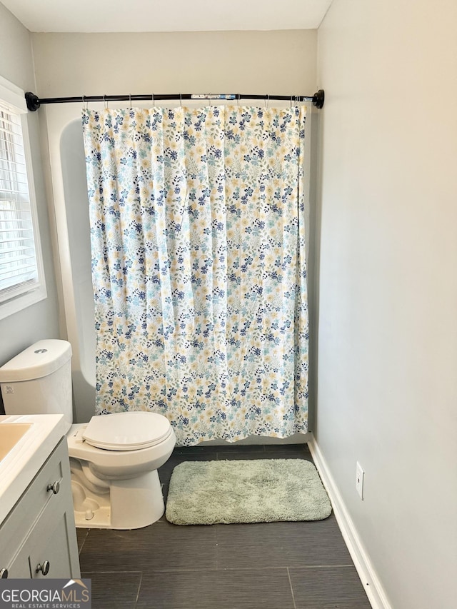 bathroom with toilet, vanity, baseboards, and a shower with shower curtain