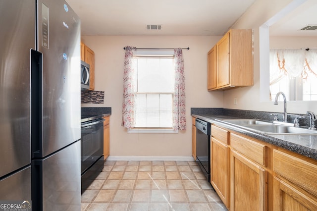 kitchen with baseboards, a sink, dark countertops, visible vents, and black appliances
