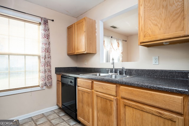 kitchen with dark countertops, plenty of natural light, dishwasher, and a sink