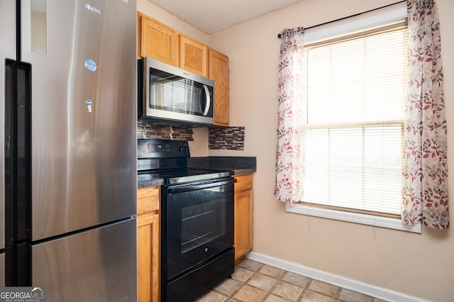 kitchen with backsplash, dark countertops, stainless steel appliances, and baseboards