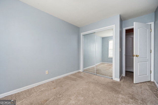 unfurnished bedroom with baseboards, carpet floors, and a closet