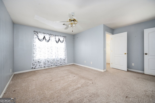 carpeted empty room featuring a ceiling fan and baseboards