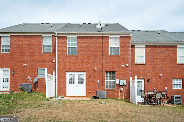 back of property featuring brick siding, central AC unit, and a yard