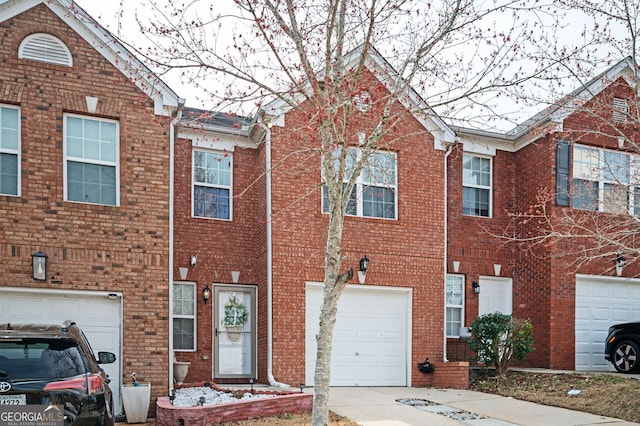 view of property with a garage, brick siding, and concrete driveway