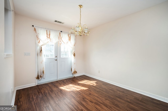 spare room featuring baseboards, visible vents, an inviting chandelier, and wood finished floors