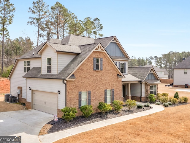 craftsman house with driveway, roof with shingles, cooling unit, board and batten siding, and brick siding