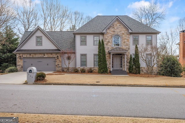 view of front facade featuring a shingled roof, a standing seam roof, metal roof, stone siding, and driveway