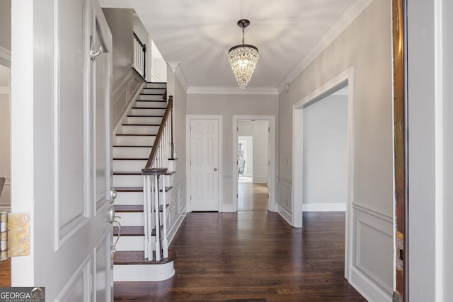 foyer entrance featuring crown molding, stairway, dark wood-type flooring, a chandelier, and baseboards