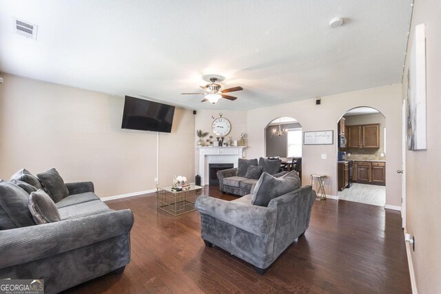 141 Back Cedar Ln, Warner Robins, GA 31093 - living room featuring arched walkways, dark wood-type flooring, a fireplace, visible vents, and baseboards