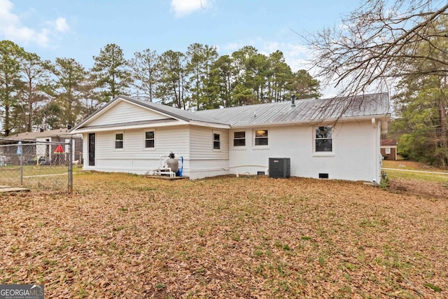 back of house featuring a lawn, central AC unit, metal roof, and fence
