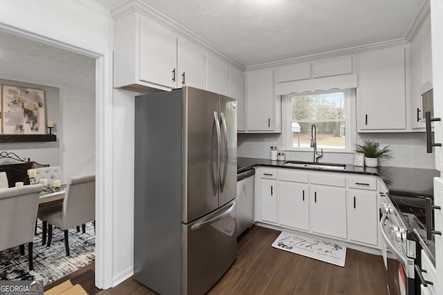 kitchen with stainless steel appliances, dark wood-style floors, a sink, tasteful backsplash, and dark countertops