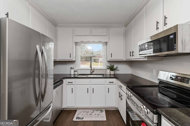 kitchen featuring white cabinets, stainless steel appliances, a sink, dark wood finished floors, and tasteful backsplash
