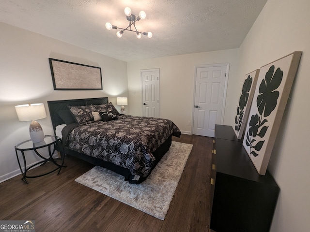 bedroom with dark wood finished floors, baseboards, a notable chandelier, and a textured ceiling