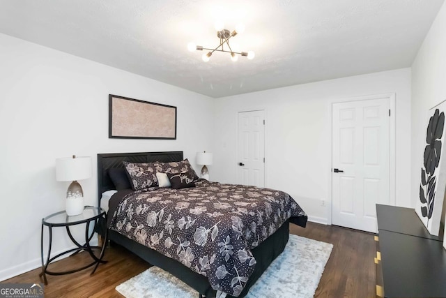 bedroom with a chandelier, baseboards, and dark wood-style flooring