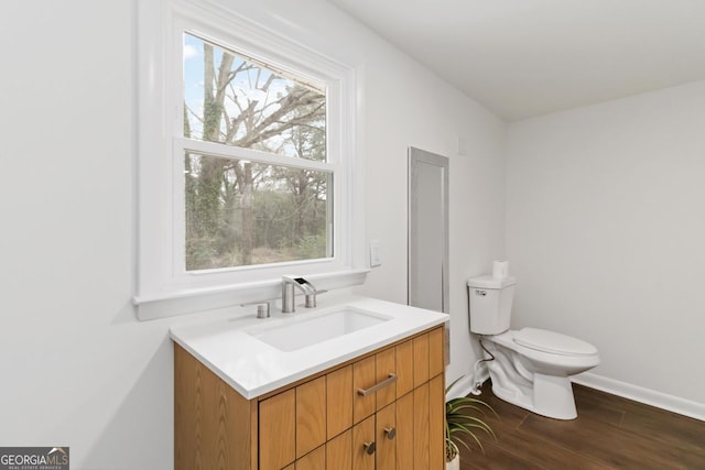 bathroom with baseboards, wood finished floors, vanity, and toilet