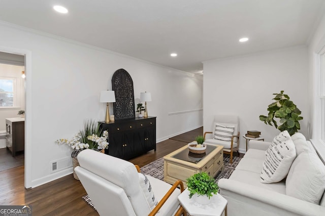 living area featuring wood finished floors, visible vents, baseboards, and ornamental molding