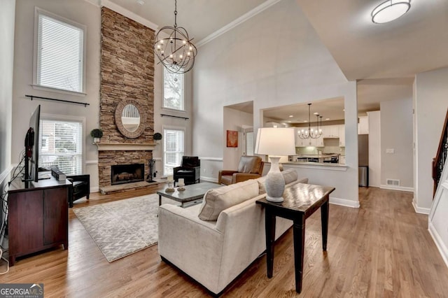 living room with light wood finished floors, a fireplace, visible vents, and an inviting chandelier