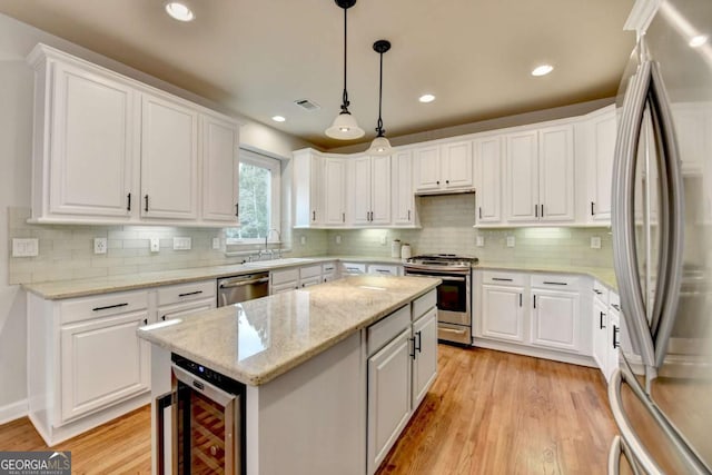 kitchen featuring wine cooler, stainless steel appliances, visible vents, a sink, and a kitchen island