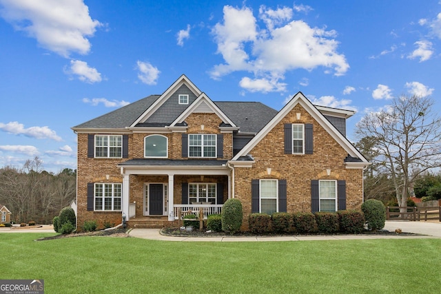 view of front facade with a porch, fence, a front lawn, and brick siding